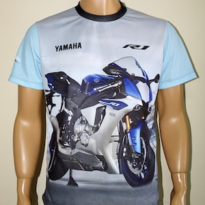 May include: A white and blue t-shirt with a graphic of a Yamaha R1 motorcycle. The shirt has the word "Yamaha" printed on the front.