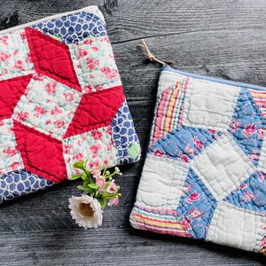 May include: Two square zippered pouches made from quilted fabric. The left pouch features a red, white, and blue floral and geometric pattern. The right pouch displays a white, blue, and pink striped and floral design with a zipper closure.