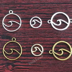 May include: Six silver and gold metal charms featuring a wave design. The charms are round and have a hole at the top for attaching to a necklace or bracelet.
