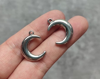 May include: Two silver crescent moon charms with a loop at the top for attaching to jewelry or other crafts.