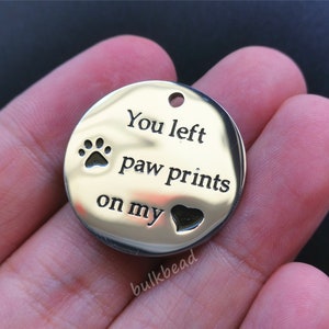 May include: Silver charm with the text "You left paw prints on my heart" and a paw print and heart design.