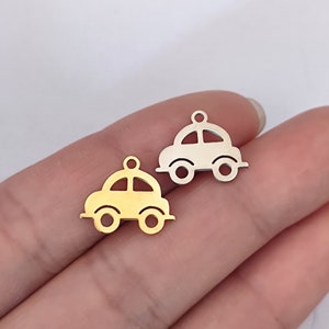 May include: Two metal car charms, one gold and one silver. The charms are in the shape of a simple car with rounded edges.