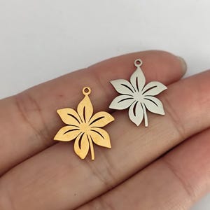 May include: Two metal flower charms, one gold and one silver, with a detailed cutout design. The charms are ideal for jewellery making or adding a touch of elegance to crafts.
