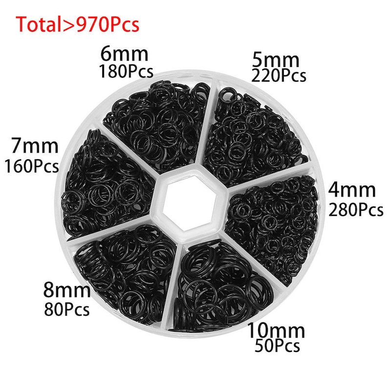 May include: A white plastic container with six compartments filled with black jump rings. Each compartment is labeled with the size of the jump rings in millimeters and the number of rings in each compartment. The total number of jump rings is 970.