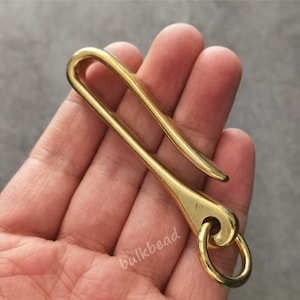 May include: A gold-colored metal hook with a ring at the end. The hook is designed to be attached to a belt loop or other item and can be used to hold keys or other small items.