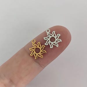 Op de afbeelding: Twee zonnenhanger, een gouden en een zilveren, met een eenvoudig, open cirkelontwerp. De hangers worden op een vinger getoond.