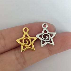 May include: Two silver and gold star-shaped charms with a spiral design. The charms have a loop at the top for attaching to jewelry.