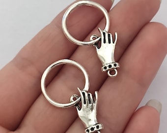 May include: Two silver-coloured charms, each depicting a hand making the 'I love you' sign, connected to a circular ring. The hand charms have a detailed design, including a bracelet. These charms are likely for jewellery making.