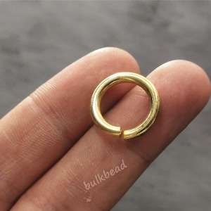Puede incluir: Un anillo de salto de metal dorado, un tipo de hallazgo de joyer&iacute;a, se muestra en un dedo.