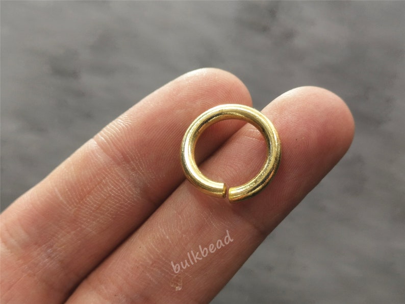Puede incluir: Un anillo de salto de metal dorado, un tipo de hallazgo de joyer&iacute;a, se muestra en un dedo.