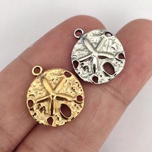 May include: Two metal sand dollar charms, one gold and one silver, with a raised starfish design. The charms have a textured surface and are ideal for jewellery making.