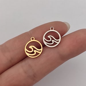 May include: Two metal charms in the shape of a circle with a wave design inside. One charm is gold and the other is silver.