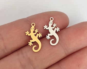 May include: Two metal gecko charms, one gold and one silver, with a loop at the top for attaching to jewelry or crafts.