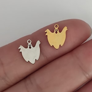 May include: Two small ghost-shaped charms, one in a polished silver tone and one in a polished gold tone. Each charm features a simple cutout design for the eyes and mouth, with a small circular loop at the top for attachment to jewellery or crafts.
