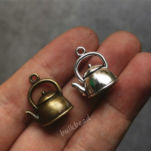 Può includere: Due ciondoli a forma di teiera argentati, uno è in argento antico e l'altro è in argento lucido.