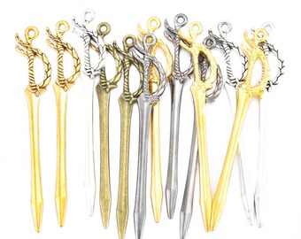 May include: A collection of 12 miniature sword charms in gold, silver, and bronze finishes. Each charm features a detailed sword design with a decorative handle.