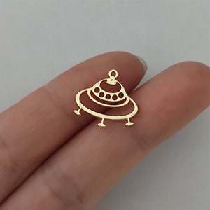 Peut inclure: Breloque en métal de couleur dorée en forme de soucoupe volante avec un sommet arrondi et un fond plat. Le breloque a un petit trou en haut pour l'attacher à un collier ou un bracelet.