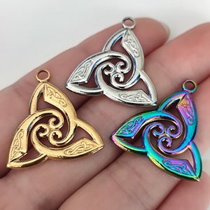 May include: Three Celtic knot pendants in different finishes: silver, gold, and iridescent. Each pendant features a intricate design of interwoven spirals and knots.