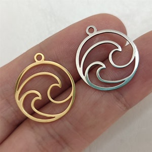 May include: Two metal wave charms, one gold and one silver, with a circular shape and a cutout design of two waves.