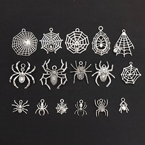 Może przedstawiać: Zbiór srebrnych metalowych zawieszek przedstawiających pająki i pajęczyny. Zawieszki idealnie nadają się do tworzenia biżuterii, scrapbookingu i innych projektów rękodzielniczych.