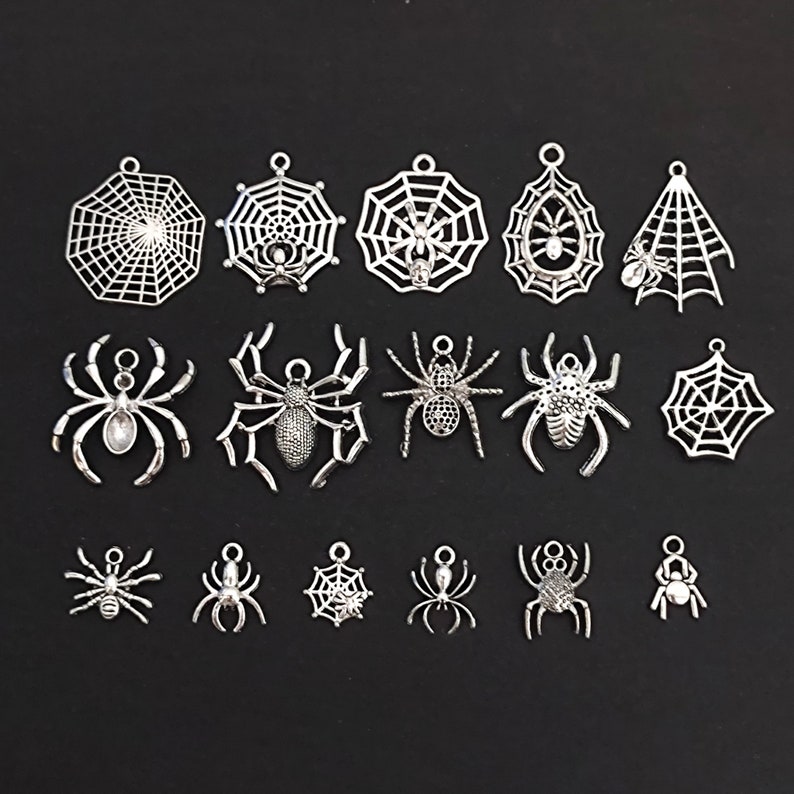 May include: A collection of silver-toned metal charms featuring spiders and spiderwebs. The charms are ideal for jewellery making, scrapbooking, and other craft projects.