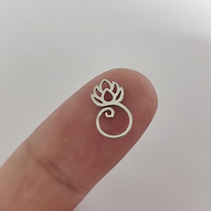 May include: A silver charm featuring a stylized lotus flower design with a swirl detail.