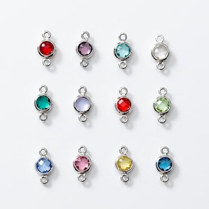 May include: Twelve silver connector charms with different colored crystal stones. The charms have two loops for attaching to jewelry.