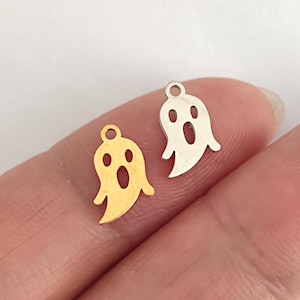 Könnte beinhalten: Zwei Geister-Anhänger aus Metall, einer golden und einer silbern, mit einem Loch oben zum Anbringen an Schmuck oder anderen Bastelarbeiten.