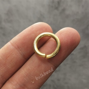 Puede incluir: Un anillo de salto de metal de color dorado. El anillo es redondo y tiene un acabado liso.