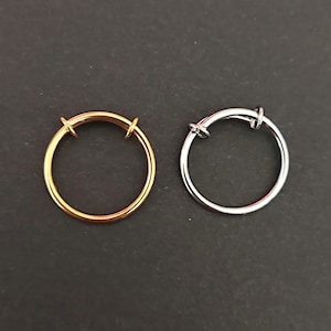 May include: Two metal rings, one gold and one silver, with a hinged opening. The rings are on a dark gray background.