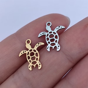 Può includere: Due ciondoli a forma di tartaruga in metallo, uno dorato e uno argentato, con un design dettagliato. I ciondoli sono perfetti per la creazione di gioielli o per l'artigianato.