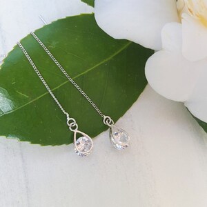 May include: A pair of silver dangle earrings with clear teardrop-shaped crystals.