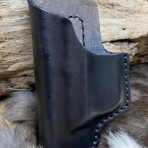 Peut inclure: Un &eacute;tui en cuir noir avec des coutures sur les bords. L'&eacute;tui est fait de cuir &eacute;pais et r&eacute;sistant et a une finition lisse.