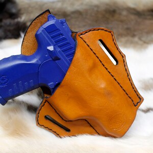 May include: A blue handgun in a brown leather holster. The holster has a stitched design and a belt loop.