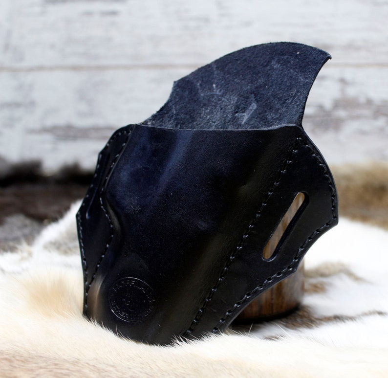 May include: A black leather holster with a stitched design and a flap. The holster is made of high-quality leather and has a smooth finish.