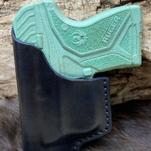 Peut inclure: Un &eacute;tui en cuir noir avec un pistolet Ruger vert &agrave; l'int&eacute;rieur.