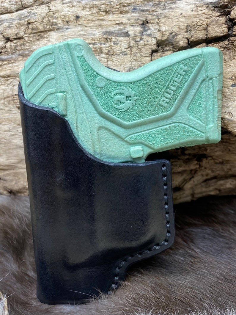 Peut inclure: Un &eacute;tui en cuir noir avec un pistolet Ruger vert &agrave; l'int&eacute;rieur.