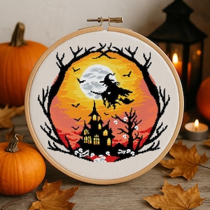 May include: A cross-stitch embroidery in a wooden hoop shows a Halloween scene. A witch flies in front of a full moon, with a haunted house and bare trees. The background is a gradient of orange, yellow, and red.