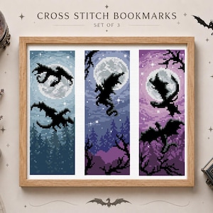 Könnte beinhalten: Ein Set aus drei Kreuzstich-Lesezeichen in einem Holzrahmen, jedes mit einer Pixel-Art-Drachensilhouette vor einem Vollmond- und Waldhintergrund in Blau-, Lila- und Lavendeltönen, mit dem Text CROSS STITCH BOOKMARKS SET OF 3.