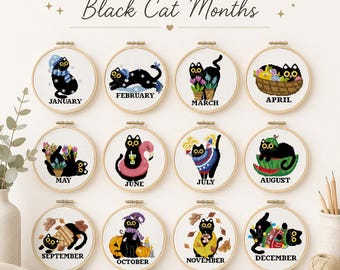 May include: A set of 12 circular embroidery hoops featuring cross-stitch designs of black cats, each representing a month of the year. The text "SET OF 12 Black Cat Months" appears at the top, with each hoop labeled with its respective month name.