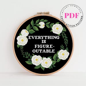 May include: Black embroidery hoop with white flowers and the text "Everything is Figure-Outable".