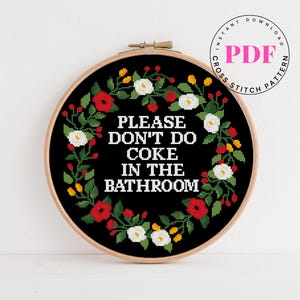 Może przedstawiać: Czarny tamborek do haftu z białym wieńcem kwiatowym i tekstem "Please don't do coke in the bathroom".