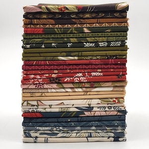 May include: A stack of folded fabric squares in various colors and floral patterns. The fabrics include shades of brown, green, red, and blue, with designs featuring leaves and flowers. The stack is neatly arranged against a white background.