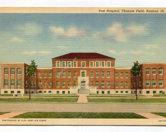 May include: Vintage postcard featuring the Post Hospital at Chanute Field in Rantoul, Illinois. The brick building has a red roof and numerous windows. The sky is blue with scattered clouds. The postcard is labeled "Photograph by U.S. Army Air Corps."