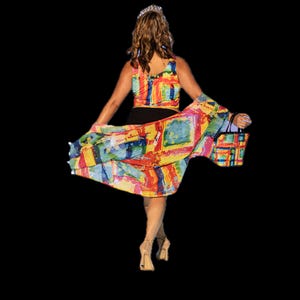 May include: A woman wearing a colorful patterned top and skirt with a black bag. The skirt is flowing and the top is cropped. The woman is wearing a crown.