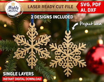 May include: Two laser-cut wooden snowflake ornaments hanging from blue and teal ribbons. The ornaments are displayed against a backdrop of Christmas tree branches and red ornaments. The image includes text that reads "LASER READY CUT FILE" and "2 DESIGNS INCLUDED".