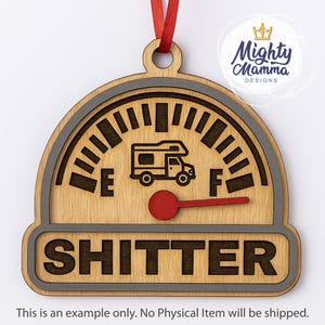 May include: Wooden ornament with a speedometer design. The gauge features a camper illustration and the word "SHITTER". The needle is red, and the ornament hangs from a red ribbon. The design includes the text "Mighty Mamma Designs".