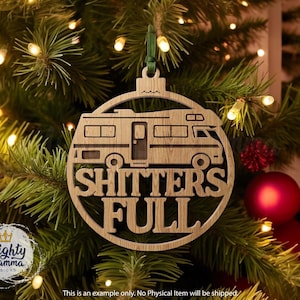 May include: A wooden Christmas ornament shaped like a camper van with the words "SHITTERS FULL" cut out. The ornament hangs from a green ribbon against a backdrop of a Christmas tree with lights and red ornaments.