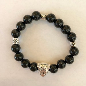 May include: Black onyx beaded bracelet with silver accents and a silver panther head charm.