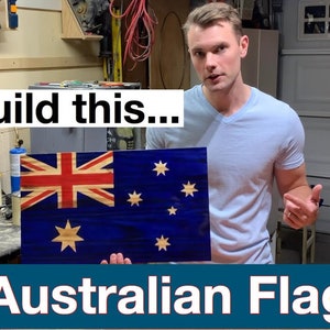May include: A man is holding up a wooden Australian flag. The flag is made of different types of wood, creating a unique wood grain pattern. The flag is blue with a white Union Jack in the top left corner and seven white stars in the bottom right corner. The text "Build this... Australian Flag" is below the flag.